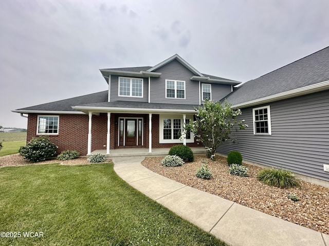 1640 Olt Rd, Columbus Grove, OH 45830 - traditional-style home with a front yard, brick siding, covered porch, and roof with shingles
