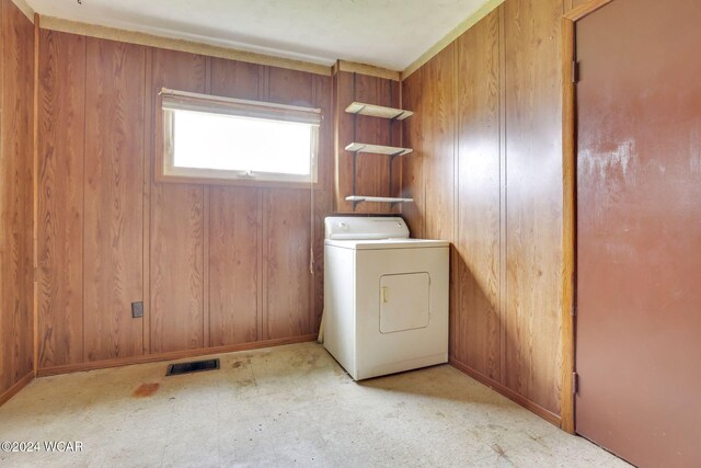clothes washing area with washer / clothes dryer and wood walls
