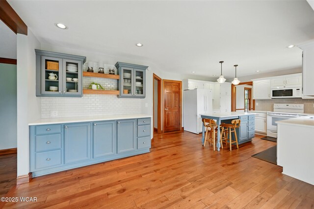 4860 Wenatchi Trl, Lima, OH 45805 - kitchen with white appliances, decorative backsplash, a breakfast bar, light wood-style floors, and a center island