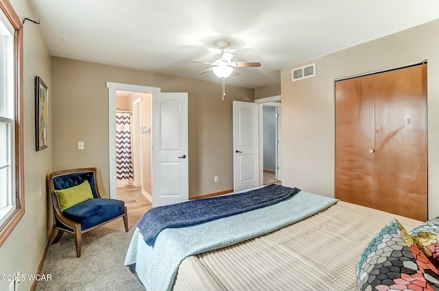 bedroom featuring ceiling fan, light colored carpet, visible vents, baseboards, and a closet