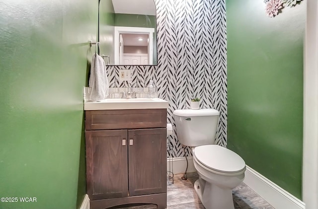 bathroom featuring toilet, baseboards, and vanity