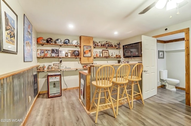 bar with a dry bar, light wood-style flooring, baseboards, and ceiling fan