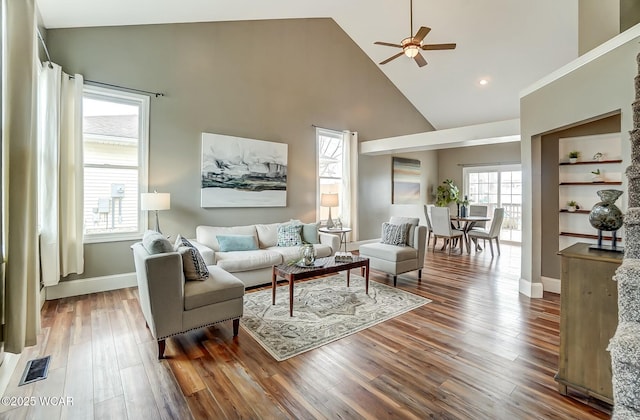 living room featuring high vaulted ceiling, wood finished floors, a ceiling fan, visible vents, and baseboards