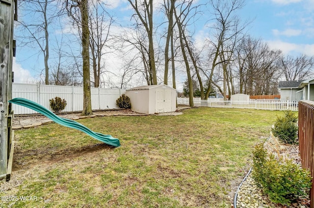 view of yard with an outbuilding, a fenced backyard, a playground, and a storage shed