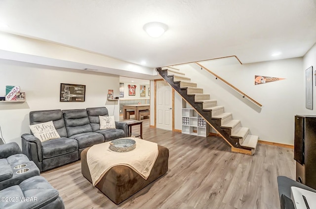 living room featuring visible vents, baseboards, stairway, and light wood finished floors