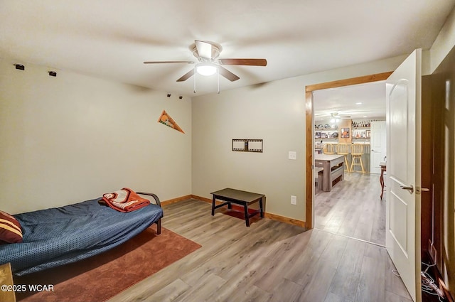 bedroom featuring a ceiling fan, light wood-style flooring, and baseboards