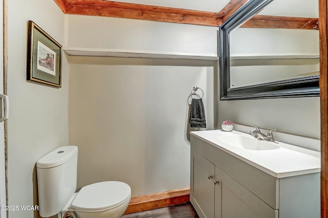 half bathroom featuring toilet, wood finished floors, and vanity