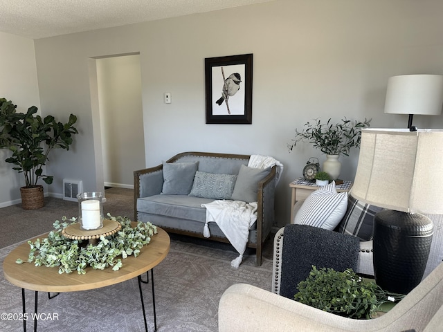 living area with visible vents, baseboards, carpet, and a textured ceiling