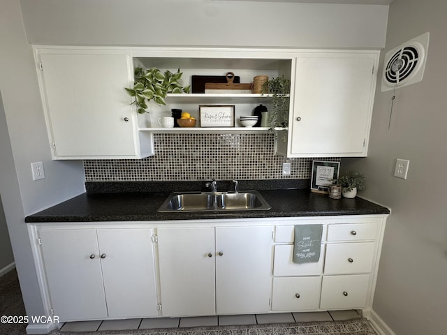 kitchen featuring dark countertops, visible vents, backsplash, open shelves, and a sink