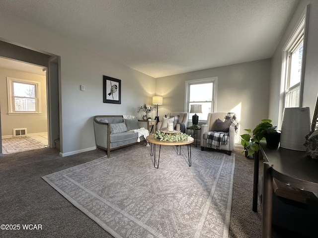 carpeted living room with visible vents, baseboards, and a textured ceiling