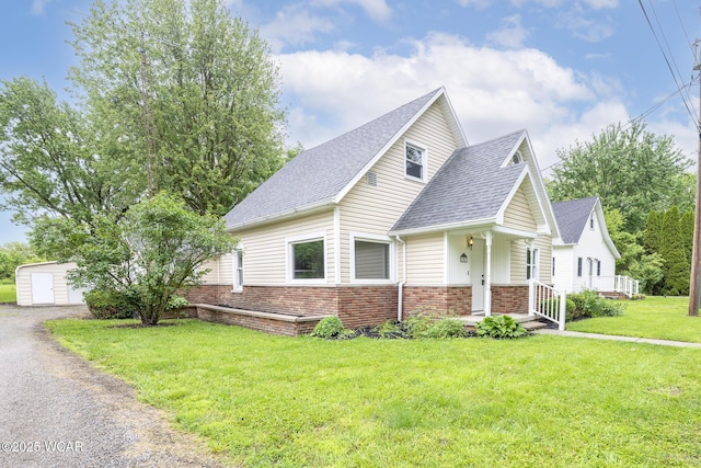 247 W State St, West Mansfield, OH 43358 - view of front of house featuring a shingled roof, brick siding, a front lawn, and driveway
