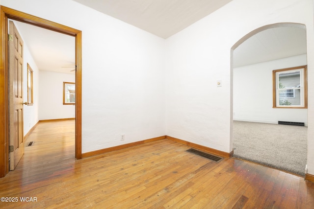 247 W State St, West Mansfield, OH 43358 - unfurnished room featuring arched walkways, baseboards, a baseboard radiator, and light wood-style floors