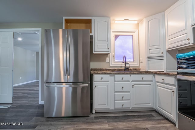 kitchen with dark hardwood / wood-style flooring, sink, white cabinets, and stainless steel refrigerator