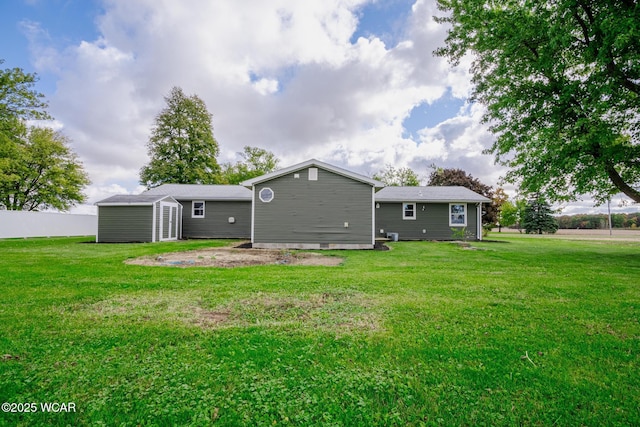 back of house with a storage unit and a lawn