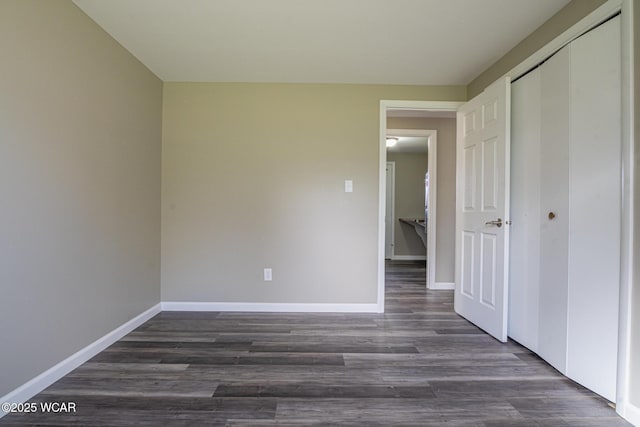 unfurnished bedroom with dark wood-type flooring and a closet