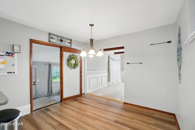 2432 Kunneke Ave, Lima, OH 45805 - unfurnished dining area featuring a chandelier, light wood-type flooring, and a wainscoted wall