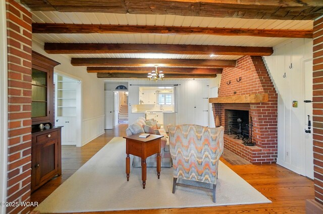 2297 June Dr, Lima, OH 45805 - living room featuring wood finished floors, a brick fireplace, a wooden ceiling with exposed beams, a chandelier, and wainscoting