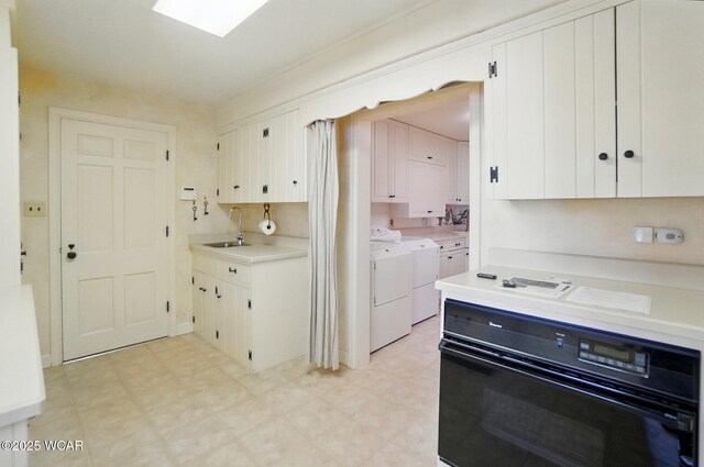 2297 June Dr, Lima, OH 45805 - kitchen with black oven, washing machine and clothes dryer, light floors, and light countertops