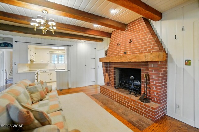 2297 June Dr, Lima, OH 45805 - living room with wood finished floors, a chandelier, a wooden ceiling with exposed beams, and a fireplace