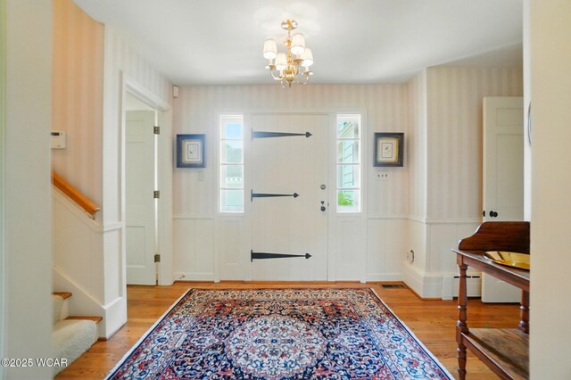 2297 June Dr, Lima, OH 45805 - foyer featuring wallpapered walls, a chandelier, light wood-type flooring, stairs, and a wainscoted wall