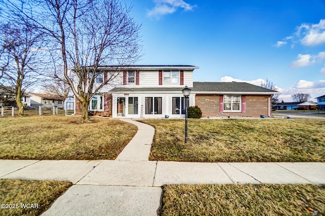 traditional home with brick siding, fence, and a front lawn