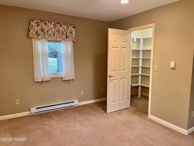 unfurnished bedroom featuring a baseboard radiator, a walk in closet, and light carpet