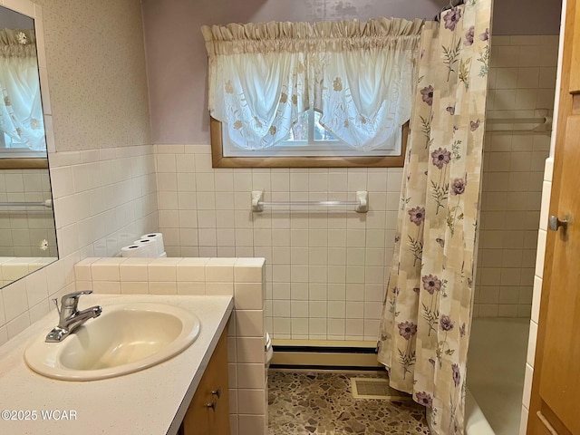 bathroom featuring tile walls, vanity, a baseboard radiator, and plenty of natural light