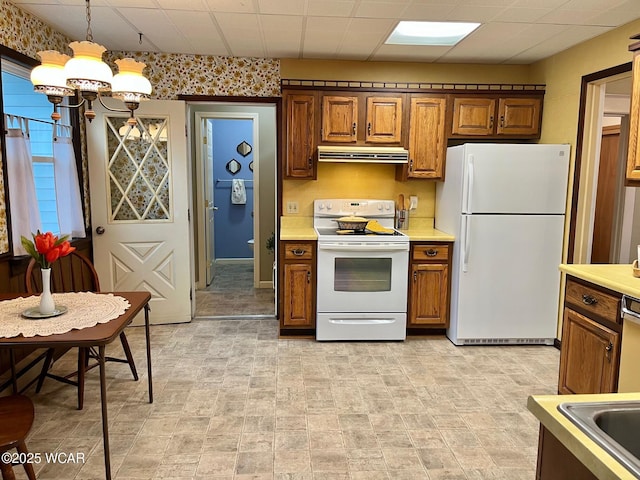 kitchen with extractor fan, decorative light fixtures, white appliances, a drop ceiling, and an inviting chandelier