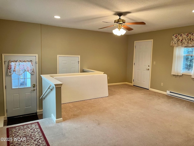 clothes washing area with ceiling fan, a baseboard heating unit, light carpet, and a textured ceiling