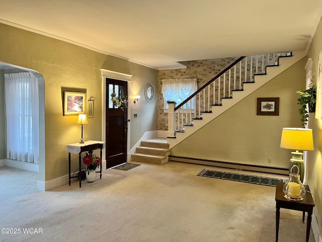 entrance foyer featuring baseboard heating, ornamental molding, and carpet