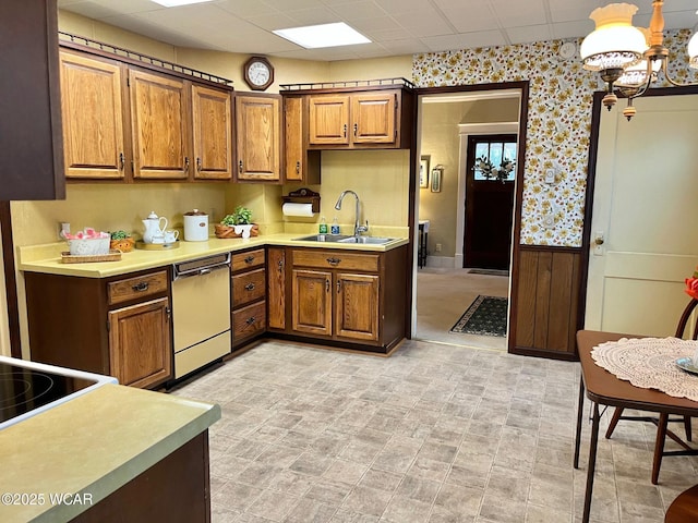 kitchen with dishwasher, sink, a drop ceiling, and decorative light fixtures