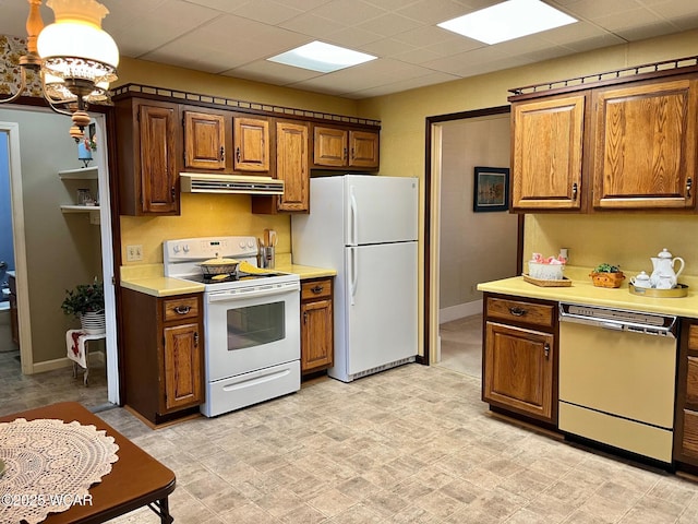 kitchen with an inviting chandelier, a drop ceiling, and white appliances