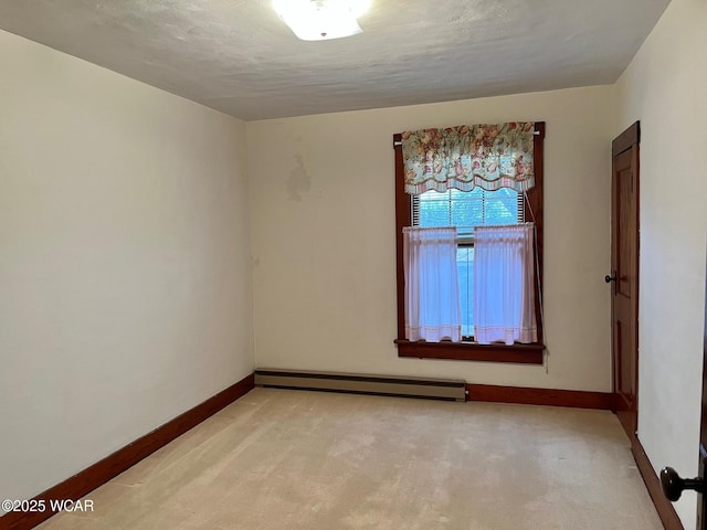 empty room featuring light colored carpet, a textured ceiling, and baseboard heating