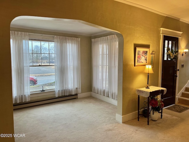 entrance foyer with a baseboard radiator, ornamental molding, and carpet flooring