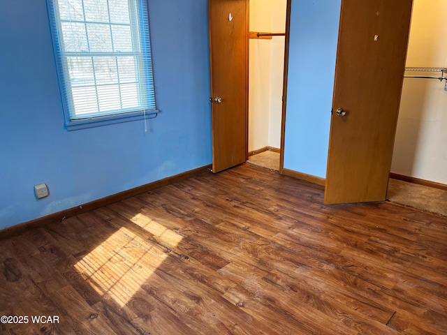 unfurnished bedroom with a closet, wood finished floors, and baseboards