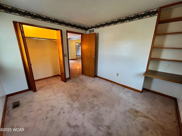 unfurnished bedroom with light carpet, baseboards, visible vents, and a closet