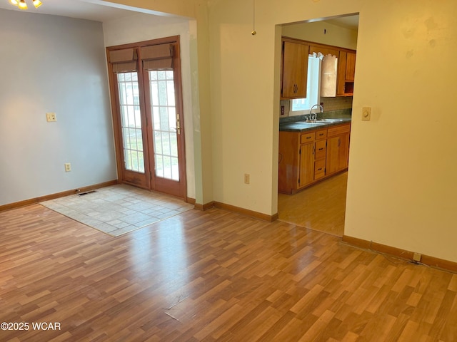 interior space featuring light wood-style flooring, a sink, visible vents, and baseboards