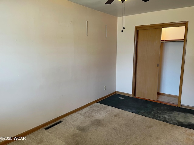 unfurnished bedroom with a ceiling fan, visible vents, baseboards, a closet, and dark carpet