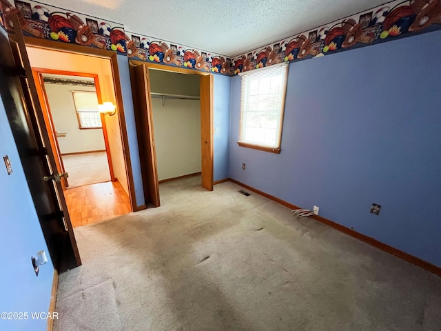 unfurnished bedroom with a textured ceiling, a closet, carpet, and baseboards