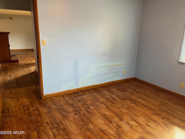 unfurnished room featuring baseboards and wood finished floors