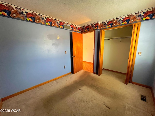 unfurnished bedroom featuring carpet, visible vents, a textured ceiling, and baseboards