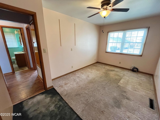 carpeted spare room featuring visible vents, ceiling fan, and baseboards