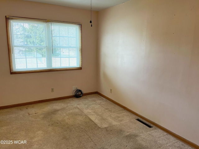 empty room with carpet, visible vents, and baseboards