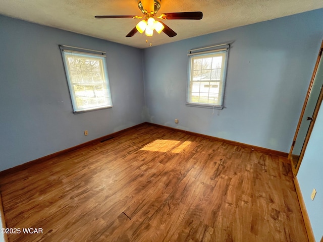 empty room featuring ceiling fan, a textured ceiling, baseboards, and wood finished floors