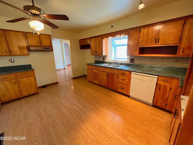 kitchen featuring brown cabinetry, white dishwasher, and a sink