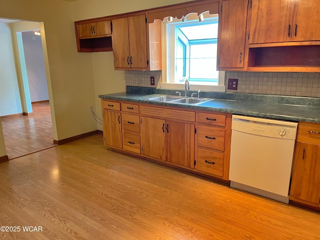 kitchen featuring dark countertops, light wood-style flooring, white dishwasher, and a sink