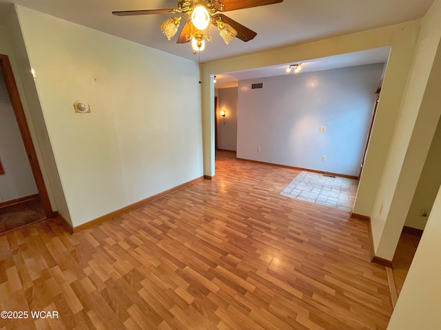 spare room featuring light wood-style flooring, visible vents, ceiling fan, and baseboards