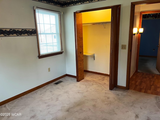 unfurnished bedroom featuring a walk in closet, a closet, visible vents, carpet flooring, and baseboards