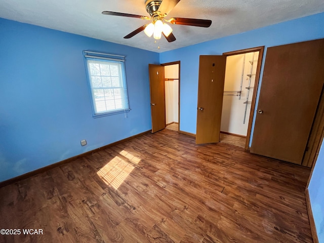 unfurnished bedroom featuring ceiling fan, a textured ceiling, baseboards, and wood finished floors