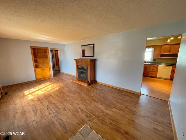 unfurnished living room with light wood-style floors, baseboards, and a textured ceiling